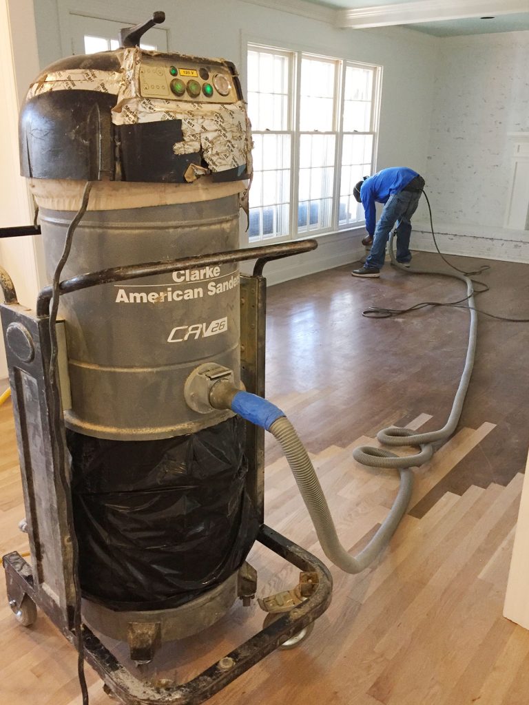 Man Sanding Hardwood Floors Using Industrial Sander