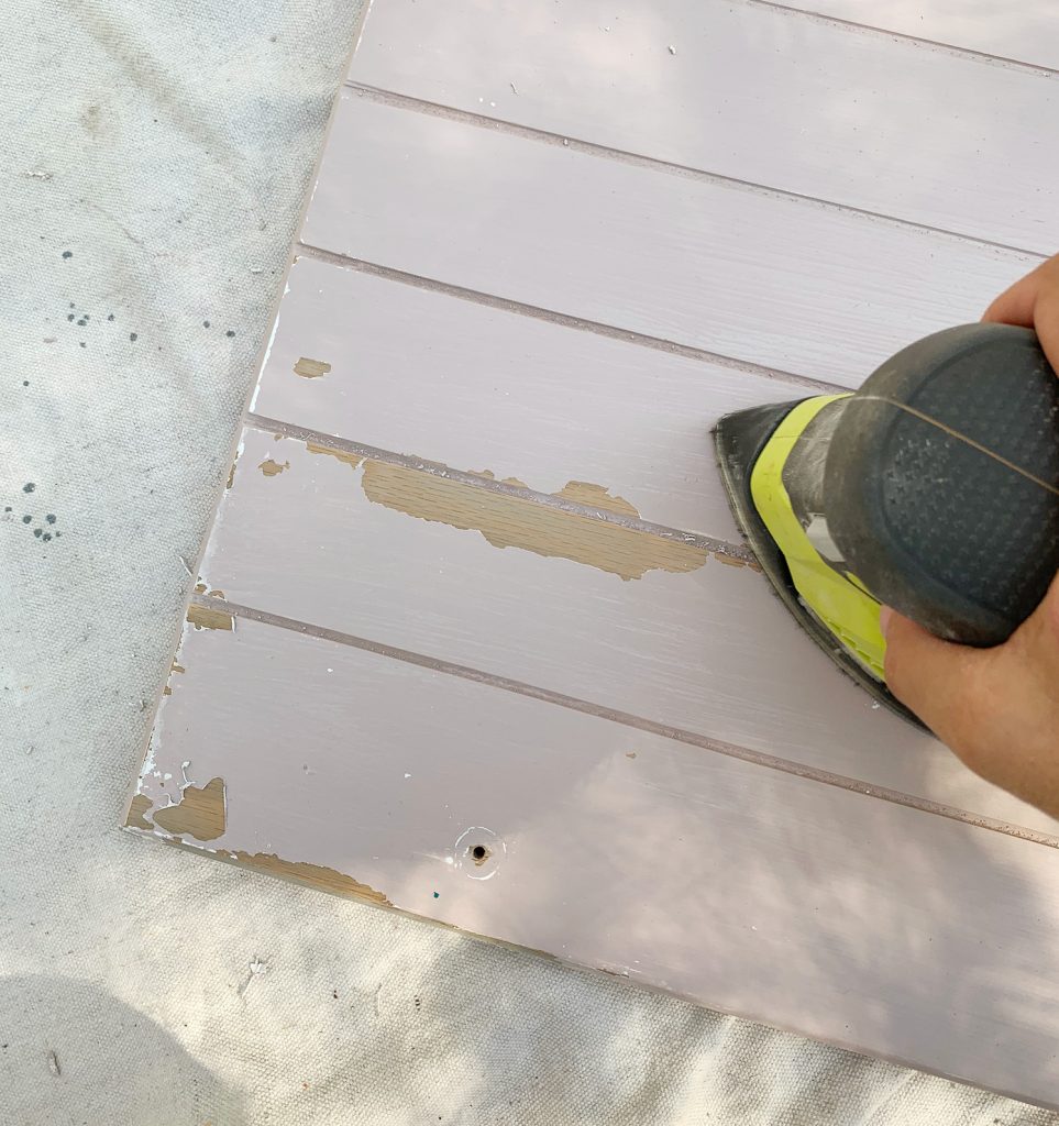 Sanding old paint drips off of wood cabinets in preparation for cabinet painting